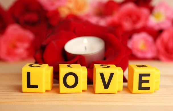 Decorative letters forming word LOVE with flowers and candle on bright background - Foto, Imagen