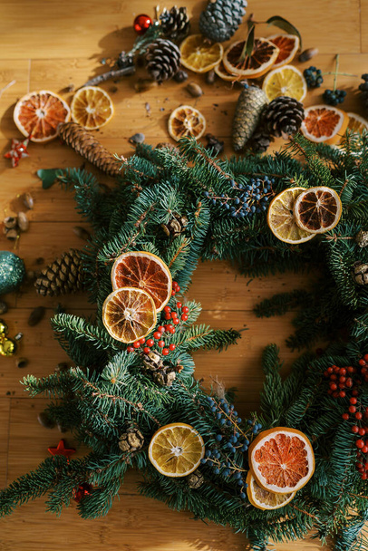 Χριστουγεννιάτικο στεφάνι από κομμάτια αποξηραμένων φρούτων και μούρων βρίσκεται στο πάτωμα. Στο πάνω μέρος. Ψιλοκομμένο. Υψηλής ποιότητας φωτογραφία - Φωτογραφία, εικόνα