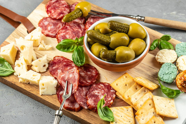 Deska Antipasto z salami, serem, chlebem i oliwkami na kamiennym tle. - Zdjęcie, obraz