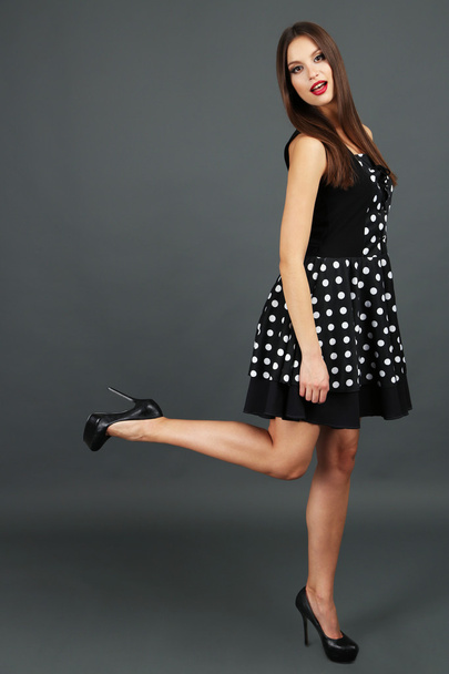 Beautiful young woman in dots dress on dark gray background - Foto, Imagem