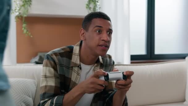 Afroamerykanin gracz facet w domu salon gry wideo konsola człowiek zabawy z wirtualną walczącą kobietą wejdź spróbować wziąć joystick chcesz grać w parę śmieszne walki uzależnienie od gier - Materiał filmowy, wideo