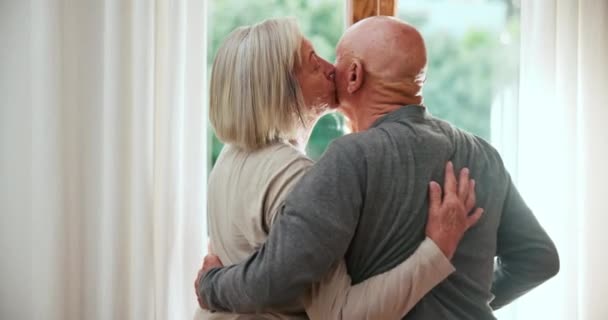 Okno, pocałunek lub uścisk starej pary z miłością, wsparciem lub opieką w małżeństwie, emeryturze lub rano. Spokój, romantyczny dojrzały mężczyzna lub starsza kobieta łączą się razem na wakacyjnej przerwie na relaks w domu. - Materiał filmowy, wideo