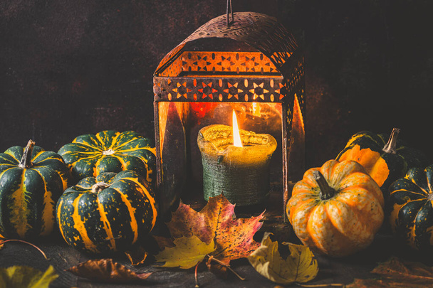 Dýně a rezavá lucerna se svíčkou pro podzimní dekoraci, tmavé dřevěné pozadí - Fotografie, Obrázek