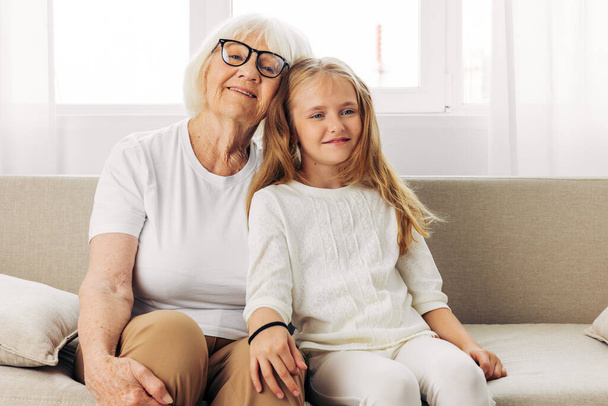 Жінка дитина похилого віку бабуся обіймає онуку щасливою любов'ю старше покоління сімейне старенька дочка диван мати сидить стиль життя додому диван - Фото, зображення