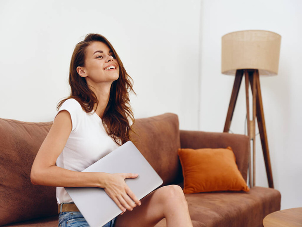 Жінка-фрілансер, що сидить на дивані з ноутбуком красива посмішка, сучасний стильний інтер'єр скандинавського способу життя, копіює простір. Високоякісна фотографія - Фото, зображення