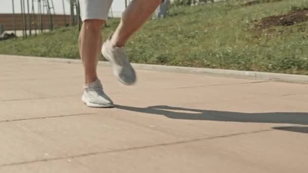 Schnappschuss in Zeitlupe von Beinen eines nicht wiederzuerkennenden Mannes, der an einem Sommertag auf der Stadtstraße läuft - Filmmaterial, Video