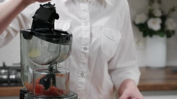 Egy nő paradicsomlevet készít a családnak gyümölcsfacsaróval. Egészséges életmód koncepció. - Felvétel, videó