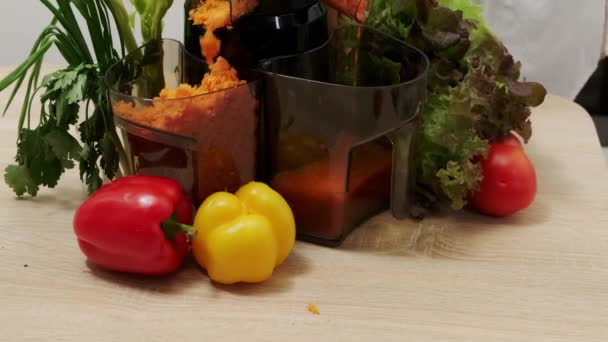 Egy nő zöldséglevet készít egy gyümölcsfacsaróval az otthoni konyhájában. Egészséges méregtelenítő vegetáriánus étrend hidegen préselt növényi extraktorral tápanyagok kivonására turmixokhoz. - Felvétel, videó