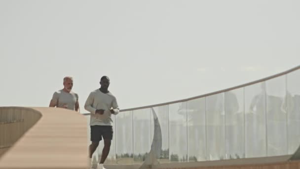 Zpomalený záběr mladého černocha mluví se starším přítelem, zatímco běží spolu venku ve městě na slunný den - Záběry, video