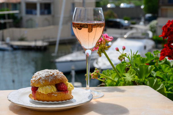 Wine and cakes of French Riviera, glasses of cold rose Cote de Provence wine and Tarte Tropezienne cake in yacht harbour of Port Grimaud, summer vacation  in Provence, France - Photo, Image