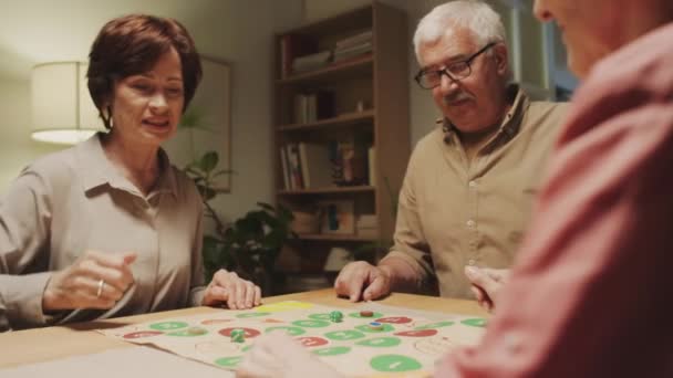 Par-dessus l'épaule des personnes âgées en utilisant des dés lors du jeu de société sur le bureau de rassemblement à la maison - Séquence, vidéo