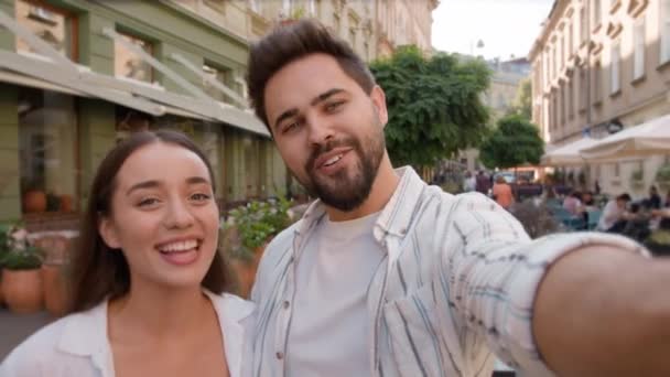 Selfie vlog boldog kaukázusi pár bloggerek lány srác séta együtt szabadban város hétvége mosolygós nő férfi nevetés rekord videó utazás blog mobiltelefon a városban szerelem érzések szórakoztató ölelés harmónia - Felvétel, videó
