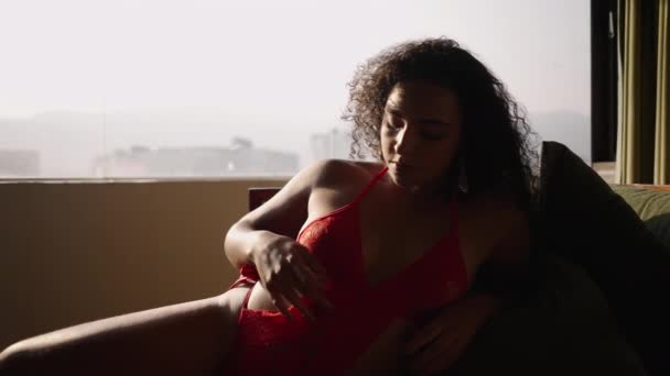 Dél-amerikai származású nő érinti a testét fekszik a kanapén - Test pozitív - Felvétel, videó