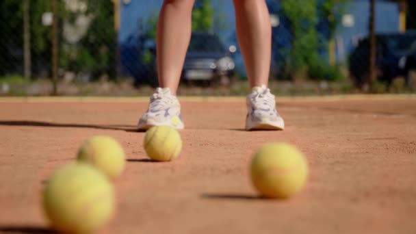 Dziewczyna tenisistka stoi na boisku i ćwiczy uderzanie piłki rakietą na ziemi. Trening siły uderzenia. Zamknij drzwi. Efekt rozmycia. Wysokiej jakości materiał 4k - Materiał filmowy, wideo