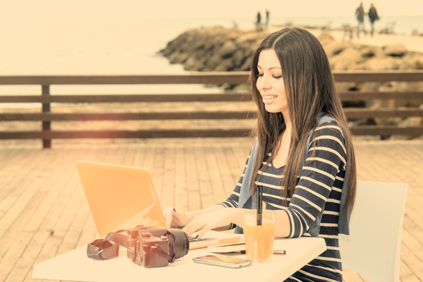junge Frau arbeitet am Laptop am Meer Warmfilter aufgetragen - Foto, Bild
