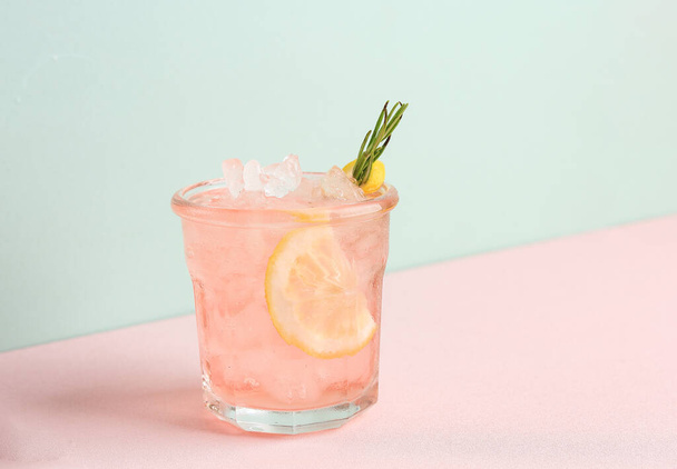 Bebida de limón rosa alcohólica rosa o limonada, cóctel con romero y rodaja de limón - Foto, Imagen