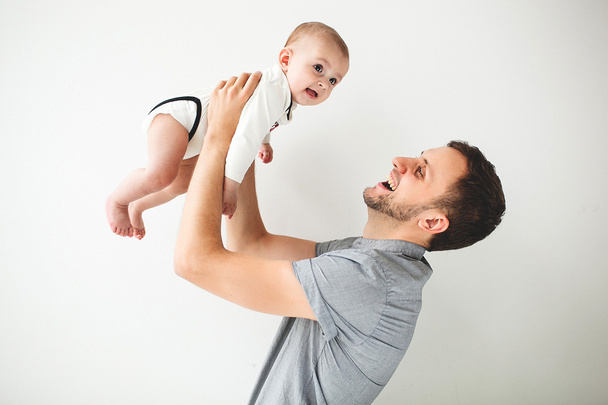 Happy father holding baby in hands over head isolated background - Fotó, kép