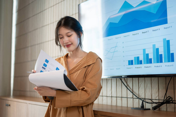 Krásná mladá asijská podnikatelka nebo finanční analytička čte informace ve svých papírech, zatímco prezentuje své finanční analýzy informací na schůzce. - Fotografie, Obrázek