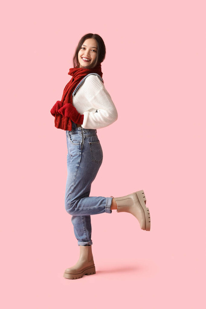 Красива молода азіатка в теплому шарфі і рукавичках на рожевому фоні - Фото, зображення