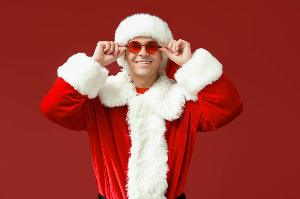 Kerstman in bril op rode achtergrond - Foto, afbeelding