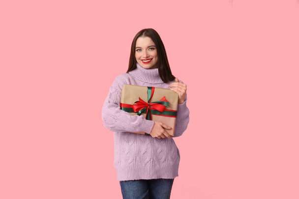 Young woman holding Christmas gift box on pink background - Photo, Image