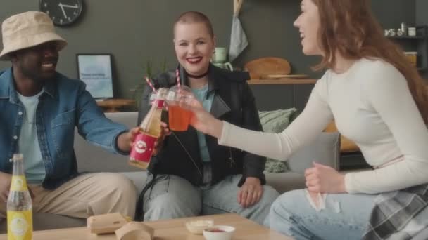Medium shot van multiraciale jonge vrienden juichen met bruisende drankjes tijdens het verzamelen in appartement overdag chatten en het hebben van goede tijd - Video