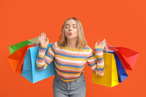 Giovane donna con borse della spesa su sfondo arancione - Foto, immagini
