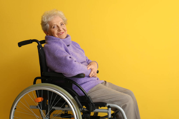 Старшая женщина в инвалидной коляске на желтом фоне - Фото, изображение