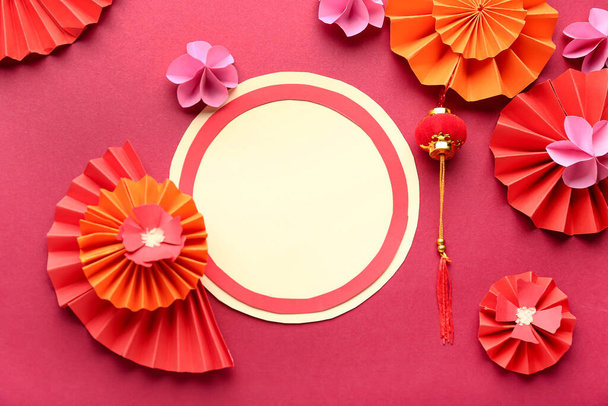 Tarjeta en blanco con abanicos, flores de papel y símbolo oriental sobre fondo rojo. Celebración de Año Nuevo - Foto, imagen