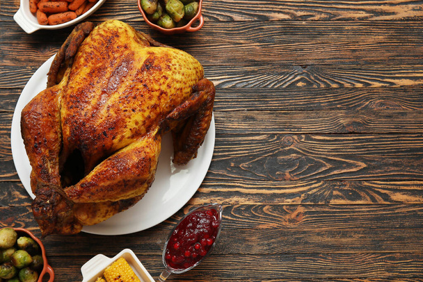Plate with tasty roasted turkey and different dishes for Thanksgiving day on wooden background - Photo, Image