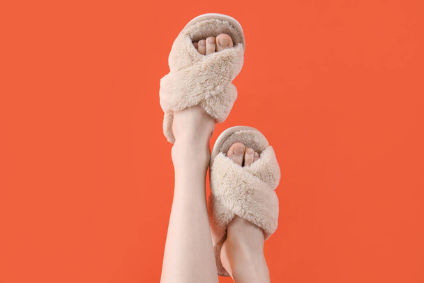 Patas femeninas en zapatillas suaves sobre fondo naranja - Foto, Imagen