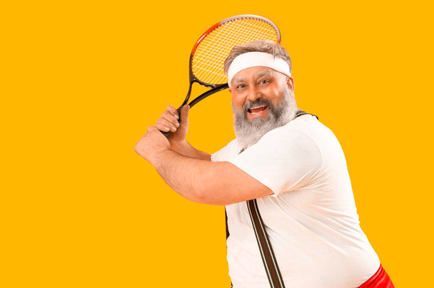 Sportieve Kerstman met racket op gele achtergrond - Foto, afbeelding