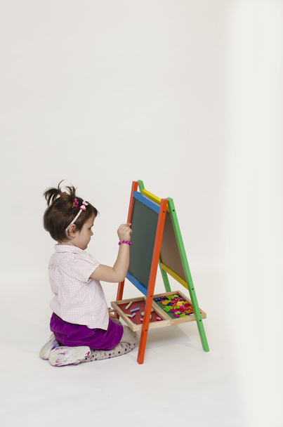 Очаровательная девочка рисует на черной доске
 - Фото, изображение