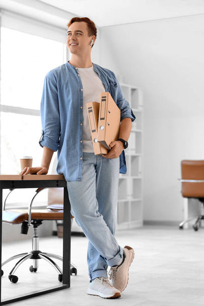 Молодой бизнесмен с папками в офисе - Фото, изображение