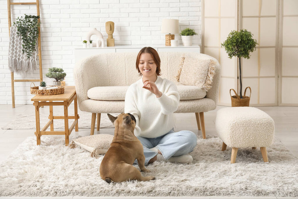 Mujer joven con lindo perro sentado en la alfombra en casa - Foto, imagen