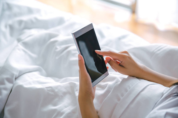 bella asiatico donna utilizzando cellulare su letto dopo wake up in moderno camera da letto a casa - Foto, immagini