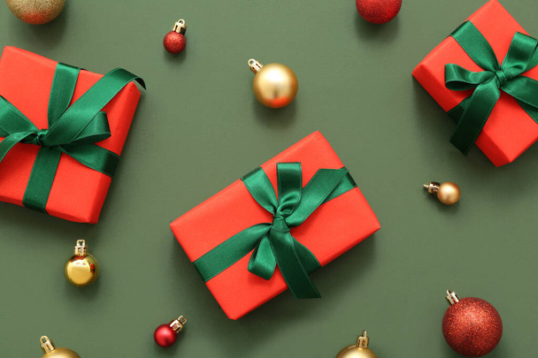 Подарункові коробки та різдвяні кульки на зеленому фоні
 - Фото, зображення