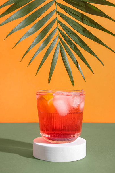 Szklanka pysznego koktajlu Negroni z kostkami lodu i liściem palmy na kolorowym tle - Zdjęcie, obraz