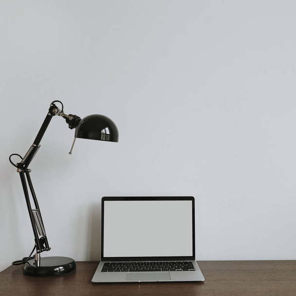 Minimalistisch kantoor thuis werkplek met laptop computer, lamp op tafel. Vooraanzicht kopieerruimte leeg model omhoog sjabloon - Foto, afbeelding