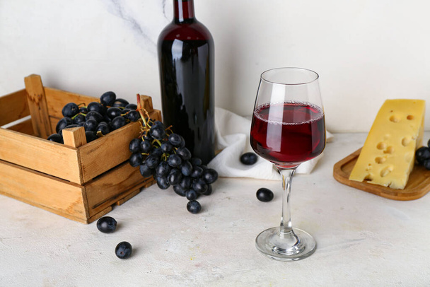 Glas en fles heerlijke wijn met druiven op tafel in de buurt van witte marmeren muur - Foto, afbeelding
