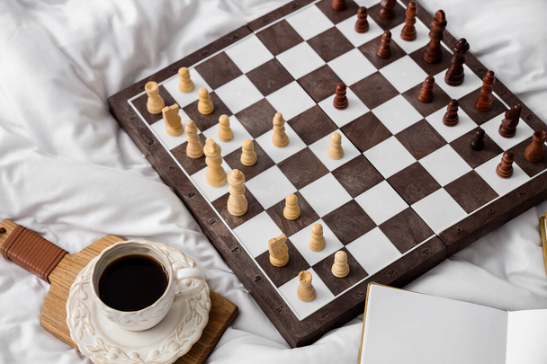 Chess board with cup of coffee on bed - Photo, Image