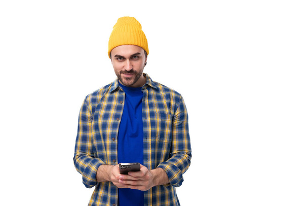 mladý brutální brunetka muž s vousem a knírkem chatování na mobilním telefonu v sociálních sítích. - Fotografie, Obrázek
