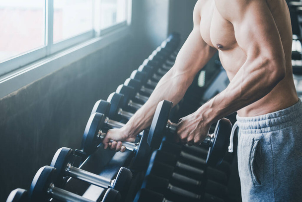 Фітнес азіатський чоловік робить вправи і піднімає гантелі ваги в спортивному тренажерному залі, здоровий спосіб життя концепції - Фото, зображення