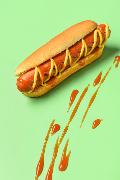 Hot dog savoureux avec moutarde et ketchup sur fond vert - Photo, image