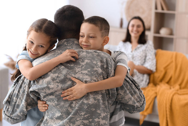 Kleine kinderen knuffelen hun militaire vader thuis - Foto, afbeelding