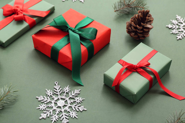 Χριστουγεννιάτικα κουτιά δώρου με κλαδιά ελάτης, κώνο και νιφάδες χιονιού σε πράσινο φόντο - Φωτογραφία, εικόνα