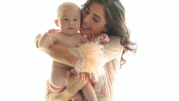Een mooie moeder houdt een klein, naakt kind in haar armen. Een jonge moeder met een prachtig kapsel en make-up houdt een kind in haar armen. Close-up, slow motion - Video
