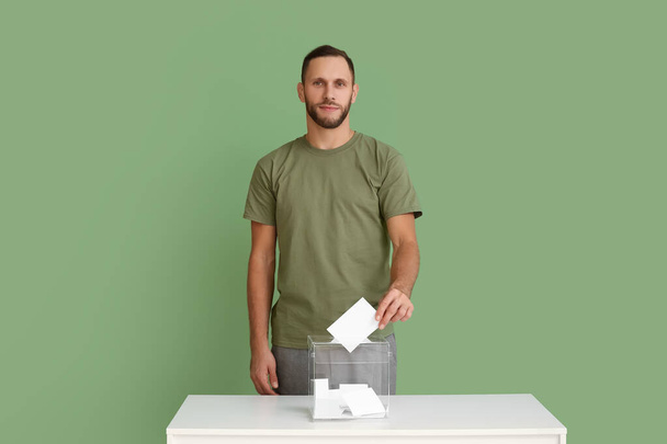 Äänestäjä lähellä vaaliuurnaa vihreällä taustalla - Valokuva, kuva