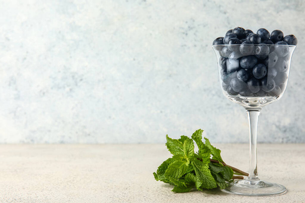 Glass with fresh blueberries and mint on white background - Photo, Image