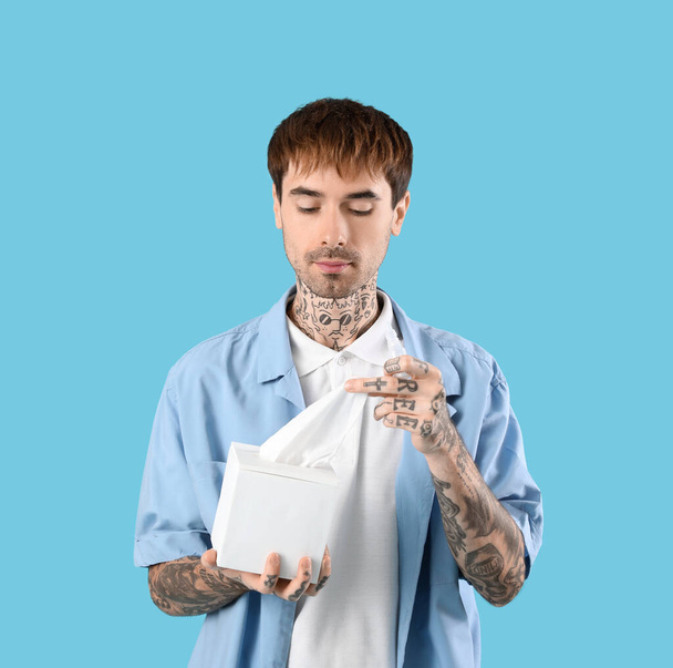 Jeune homme allergique avec des gouttes nasales et des tissus sur fond bleu - Photo, image